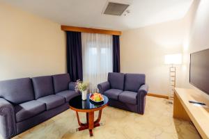 uma sala de estar com um sofá e uma mesa em Dedeman Oskemen Tavros Hotel em Ustʼ-Kamenogorsk