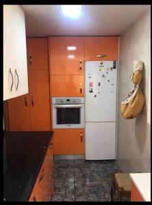 eine Küche mit Holzschränken und einem weißen Kühlschrank in der Unterkunft Mar y Gibraltar: ¡Tu Refugio! in La Línea de la Concepción