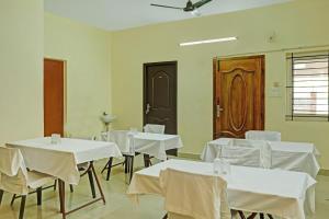 uma sala de jantar com mesas brancas e cadeiras brancas em Hotel Orchid Residency Medavakkam em Chennai