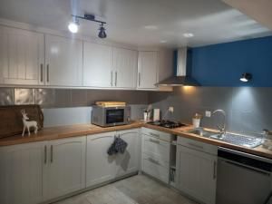 uma cozinha com armários brancos, um lavatório e um micro-ondas em La Maison Bleue em Sarlat-la-Canéda