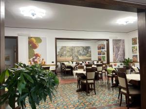 uma sala de jantar com mesas, cadeiras e plantas em Hotel Villa Giovanna em Torre Suda