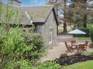 a stone cottage with a table and an umbrella at Elizabeth Lodge in Alford