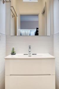 W białej łazience znajduje się umywalka i lustro. w obiekcie Apartment Suzzani 273 - Interno A4 w Mediolanie