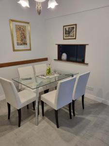 comedor con mesa de cristal y sillas blancas en Elegante 3 dormitorios en Buenos Aires