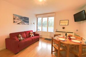 a living room with a red couch and a table at L'Ourson Randonneur - Station de ski à 600m in La Bresse