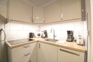 a kitchen with white cabinets and a sink at L'Ourson Randonneur - Station de ski à 600m in La Bresse