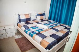 a bedroom with a bed with a blue curtain at GARDEN INN by AIRPORT inn ltd in Kigali