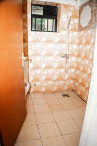 a bathroom with a shower and a tiled floor at GARDEN INN by AIRPORT inn ltd in Kigali