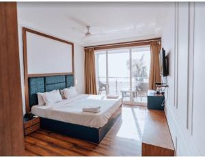 een slaapkamer met een groot bed en een groot raam bij R K Habbana Beach Resort, Baga, Goa in Baga