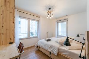 a bedroom with a bed and a desk and windows at L'Œuvre dArt - Appartement avec parking privé in Noisy-le-Grand