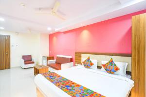 Un dormitorio con una cama grande y una pared rosa en FabHotel Prime SYN Grand, en Hyderabad