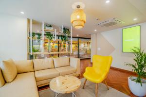 a living room with a couch and a yellow chair at Bloom Hotel - Medicity Gurugram, Near Medanta Hospital in Gurgaon