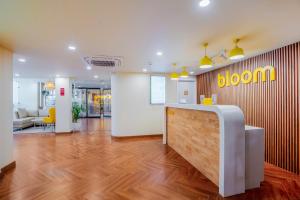 an office with a reception desk and a bloom sign on the wall at Bloom Hotel - Medicity Gurugram, Near Medanta Hospital in Gurgaon