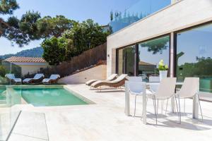 um pátio com cadeiras brancas e uma piscina em Villa Rosalicia em Tossa de Mar