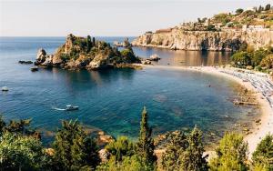 a beach with a group of people in the water at New Naxos Village in Giardini Naxos