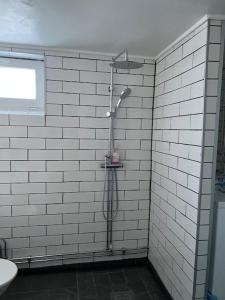 uma casa de banho com um chuveiro numa parede de azulejos brancos em Hedén Apartment em Kållered