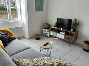 a living room with a couch and a tv at Havre de tranquillité à 13Kms des plages de Royan in Le Gua