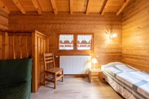 ein Schlafzimmer mit einem Bett und einem Stuhl in einer Hütte in der Unterkunft Gîte Tournette in Thônes