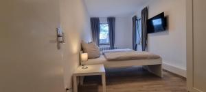 um pequeno quarto com uma pequena cama e uma televisão em 2-Bett Appartment im Boardinghaus Elisabeth em Dinslaken