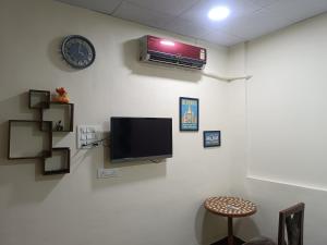 a wall with a tv and a clock on a wall at Blue Diamond Guest House in Pune