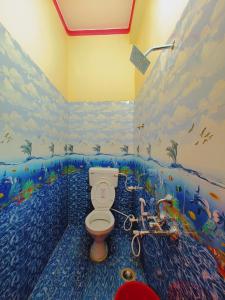 a bathroom with a toilet with a mural on the wall at Aayu Parth Residency 300 M from Ram Janam Bhumi in Ayodhya
