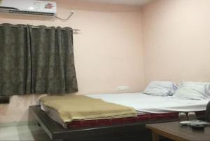 a room with a bed and a window and a desk at Hotel Jai Palace Wardha in Wardha