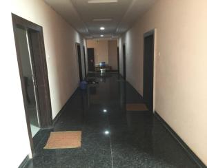 an empty hallway of a building with black floors and doors at Hotel Jai Palace Wardha in Wardha