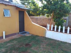 ein gelbes Haus mit einer Tür und einem Zaun in der Unterkunft Recanto do Meu Tio in Chimoio