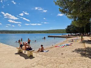 a group of people sitting on a bench on a beach at Small apartment near the beach in Gornji Karin in Anić