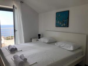 a white bedroom with a bed with towels on it at Penthouse apartment with panoramic oceanview in Krimovice