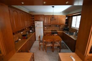 una cucina con armadi in legno, tavolo e frigorifero di Augoustinos - Sea Side Luxury Apartments a Artemida