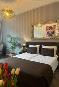 a bedroom with a bed with a mirror and flowers at Hotel Orion in Rotterdam