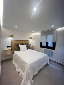 a bedroom with a white bed and a tv at Loft Anfiteatro Cudillero in Cudillero