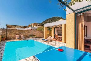 a pool with a ping pong table next to a house at Villa Zante in Barbati