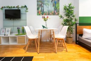 - un salon avec une table, des chaises et une télévision dans l'établissement FullHouse - Leipzig - Nord6 - Jungle Apartment, à Leipzig