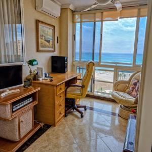 oficina con escritorio y ordenador con vistas al océano en Beachfront Nautical Apartment, en Benimagrell