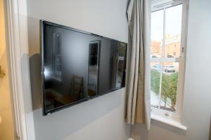 einen großen Flachbild-TV an einer Wand neben einem Fenster in der Unterkunft Pass the Keys Lincoln room at Tavmar Apartments in Lincoln