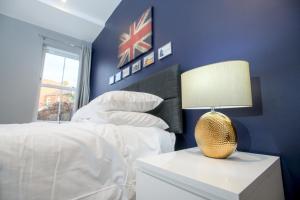 ein blaues Schlafzimmer mit einem Bett und einem Tisch mit einer Lampe in der Unterkunft Pass the Keys Lincoln room at Tavmar Apartments in Lincoln