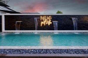 a swimming pool in front of a wall with a fountain at Nue Hatyai Pool Villa in Hat Yai