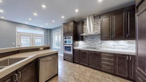 a kitchen with dark wood cabinets and a stone wall at Luxurious Stay in the Heart of Community in Brampton