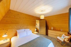 1 dormitorio con 1 cama y pared de madera en Cottage 3 chambres - Chaleureux chalet pour 6 