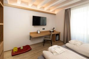 a room with two beds and a desk with a television at Hotel Margherita in Livigno