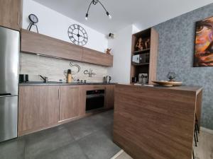 uma cozinha com armários de madeira e um frigorífico de aço inoxidável em Q Apart Gold-3 Pokoje, Garaż, Netflix, Klimatyzacja, FV, em Łódź