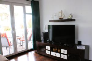 een woonkamer met een flatscreen-tv en een balkon bij Residenz Prorer Wiek App 10 strandnah, mit Balkon by Unsere Urlaubszeit in Binz