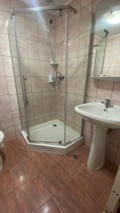 a shower with a glass door next to a sink at Pension La Viorel Isaila in Sibiu