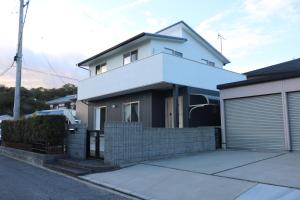 una casa blanca con una puerta y un garaje en Vacation House YOKOMBO ANNEX en Naoshima