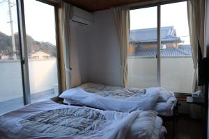 直島町にあるVacation House YOKOMBO ANNEXの大きな窓付きの客室で、ベッド2台が備わります。