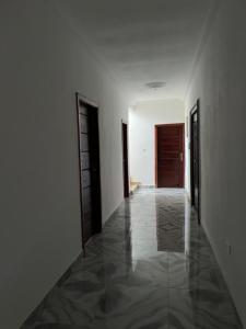 un corridoio vuoto con due porte e pavimento piastrellato di Serene Hostel a Aboman