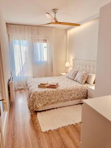 een witte slaapkamer met een bed en een plafondventilator bij El Rincon de Tasio in Corella