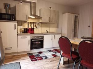 cocina con armarios blancos, mesa y sillas en Pension Danzer en Oberhof